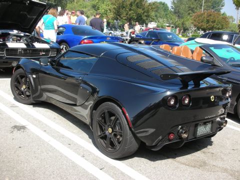 1998 Ford Crown Victoria - A black Lotus Elise is parked at a car meet, showing its distinctive rear end and custom exhaust system.