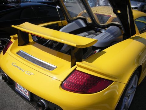 1998 Ford Crown Victoria - A yellow Porsche Carrera GT is seen from the rear with its engine compartment open, revealing the V10 engine.
