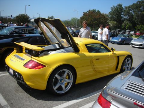 1998 Ford Crown Victoria - A yellow Porsche Carrera GT is parked with its engine cover open, surrounded by other vehicles at a car meet.
