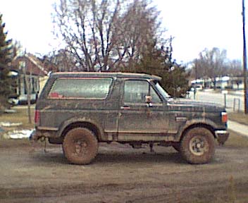 Side view of a 1987 Ford Bronco in a muddy setting