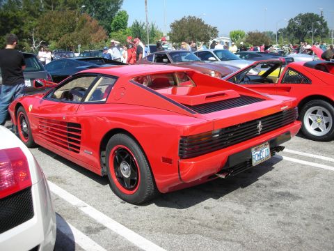 1998 Ford Crown Victoria - A red Ferrari Testarossa is parked in a lot with several other vehicles visible.