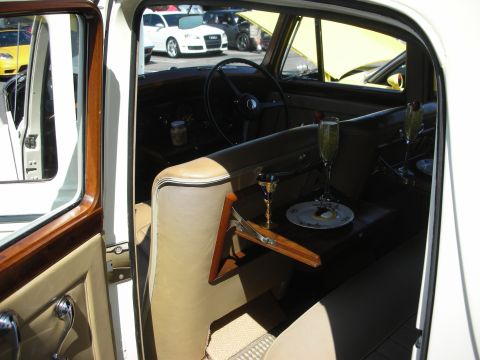 1998 Ford Crown Victoria - The interior of a classic car is shown, with two champagne glasses and a small plate on a fold-down tray.