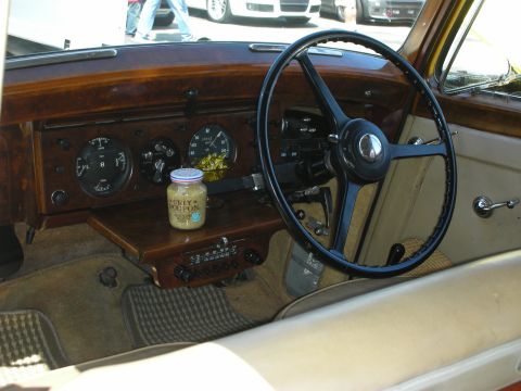 1998 Ford Crown Victoria - A jar of Grey Poupon sits on the dashboard of a classic car's interior, with other vehicles visible outside.
