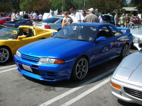 1998 Ford Crown Victoria - A blue Nissan Skyline GT-R is parked at an outdoor car show with other vehicles and people around.