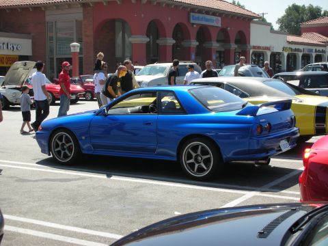 1998 Ford Crown Victoria - A blue coupe with a prominent rear spoiler is seen from the side at a car meet.
