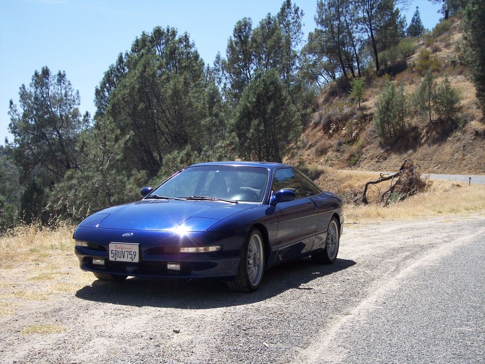 Blue Ford Probe coupe on gravel roadside pullout, front three-quarter view