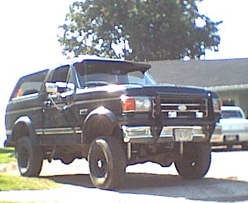 1989 Ford Bronco - This 1989 Ford Bronco is parked in front of a building with another car behind it.