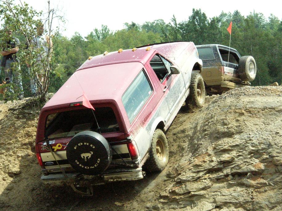 Red Ford Bronco climbing a steep, rocky incline with another SUV behind it