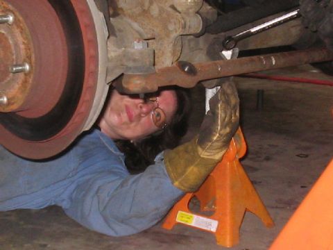 1979 Ford Bronco - A person works on the undercarriage of a vehicle, focusing on suspension parts.