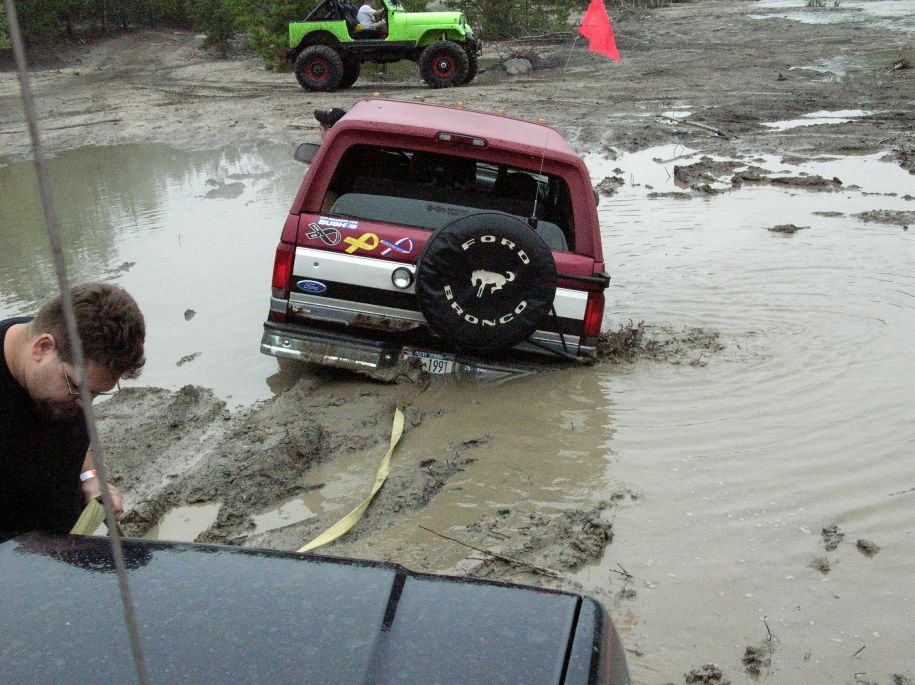 1991 Ford Bronco stuck in mud, with a green Jeep in the background