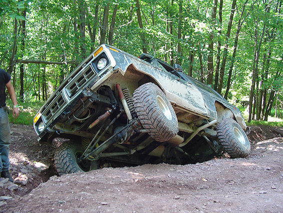 Off-road vehicle tilted on its side, showing suspension and large tires