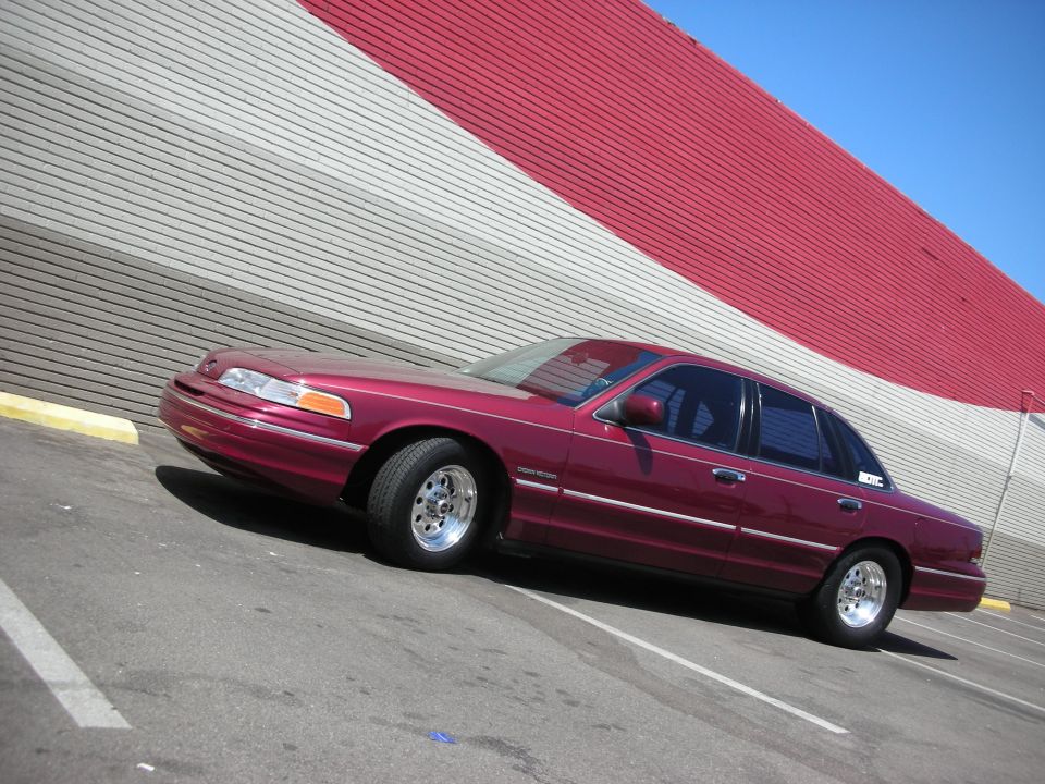 Maroon 1992 Ford Crown Victoria parked in a lot with a red and grey striped building in the background