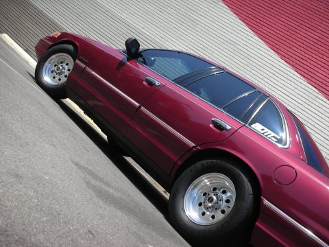 1992 Ford Crown Victoria - A maroon 1992 Ford Crown Victoria is viewed from a three-quarter front angle, its chrome accents and custom wheels.