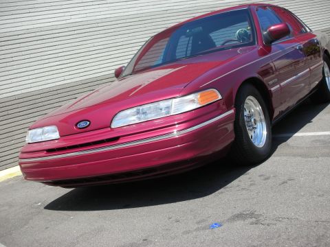 1992 Ford Crown Victoria - A red 1992 Ford Crown Victoria is parked in front of a textured wall.