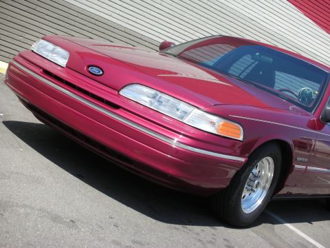 1992 Ford Crown Victoria - Front end of a red 1992 Ford Crown Victoria with chrome wheels.