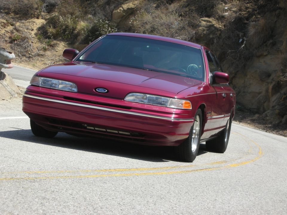 Maroon 1992 Ford Crown Victoria driving on a winding road