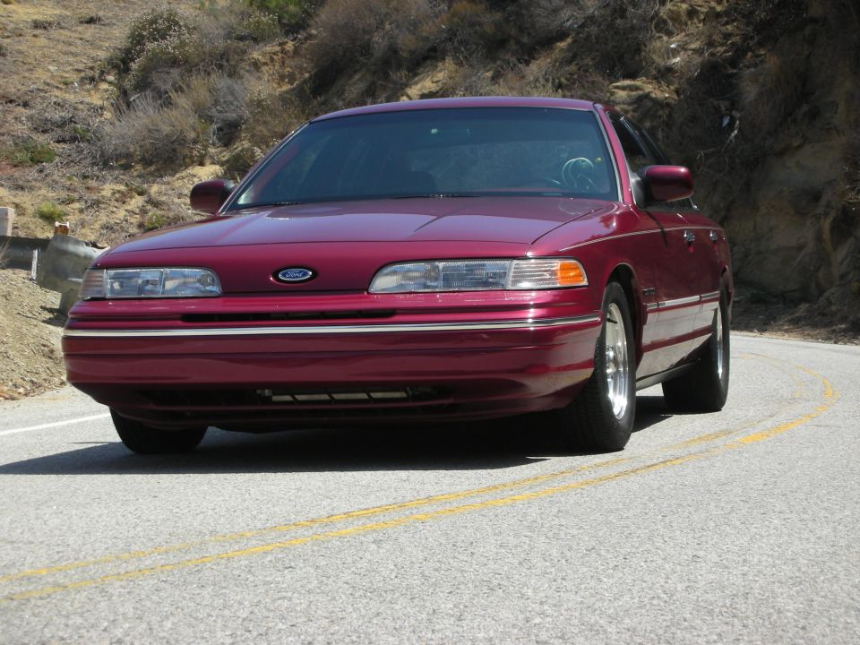 Maroon 1992 Ford Crown Victoria, front view, driving on a winding road