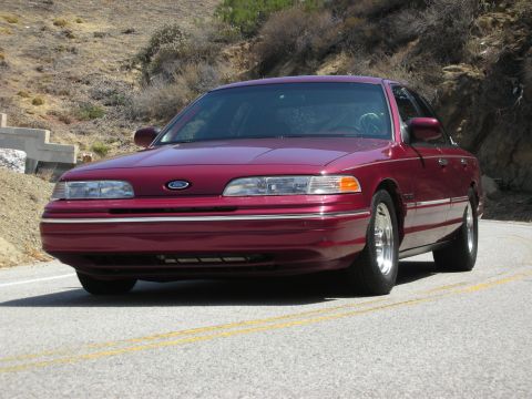 1992 Ford Crown Victoria - A maroon 1992 Ford Crown Victoria is seen from the front on a winding road.