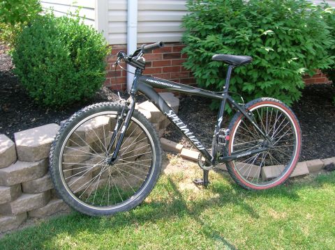 1997 Ford Probe - A Specialized mountain bike is parked outdoors next to landscaping and a house wall.