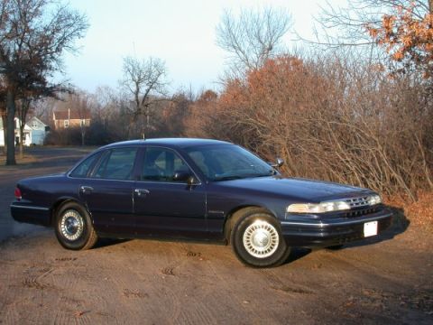 1995 Ford Crown Victoria - This 1995 Ford Crown Victoria is shown in a three-quarter front view, parked outdoors on a dirt road.