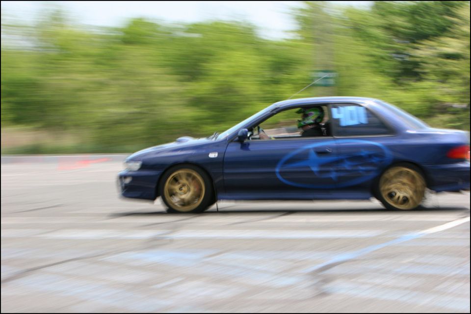 Blue Subaru Impreza WRX STI coupe with gold wheels and large side decal, number 400 on door, on a race track