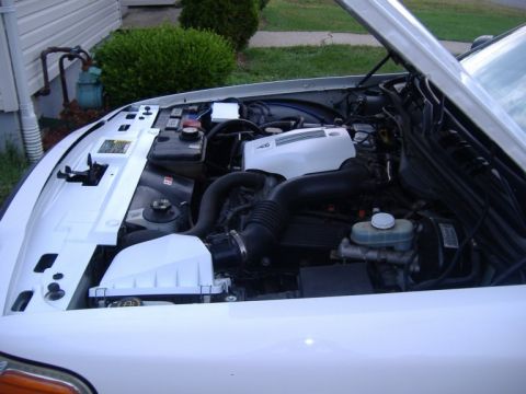 2003 Ford Crown Victoria - The engine compartment of a white vehicle is visible with the hood raised, revealing the motor and associated components.