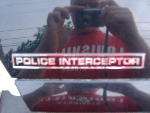 2003 Ford Crown Victoria - A 'Police Interceptor' badge is visible on the vehicle's exterior, with a reflection of the photographer.