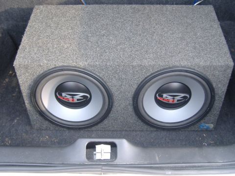 2003 Ford Crown Victoria - A close-up view of a dual subwoofer box installed in the trunk of a vehicle.