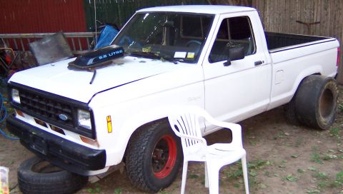 1978 Ford Bronco - A white pickup truck is parked outside with a hood scoop and large rear tires.