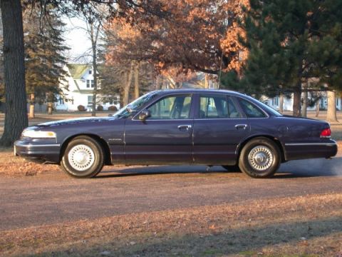 1995 Ford Crown Victoria - This 1995 Ford Crown Victoria is seen from the side, parked outdoors on a dirt road.