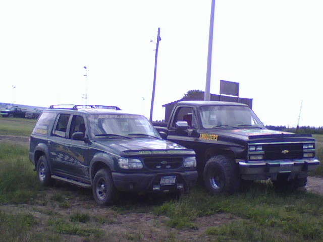 Green SUV and black pickup truck parked on grass