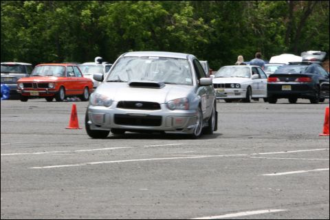 2001 Mercury Grand Marquis - A silver Subaru WRX navigates a course marked by orange cones, with other vehicles visible in the background.