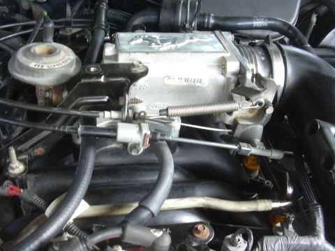 1996 Ford Crown Victoria - Engine intake manifold and throttle body assembly with visible Mustang emblem and fuel injectors.