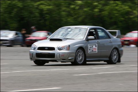 2001 Mercury Grand Marquis - Silver Subaru Impreza WRX STI sedan competes on a race track, with other vehicles visible in the background.