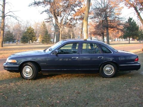 1995 Ford Crown Victoria - This 1995 Ford Crown Victoria is shown from the side in a grassy area with trees.