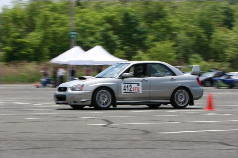2001 Mercury Grand Marquis - Silver Subaru Impreza WRX STI sedan navigates a race track, indicated by cones and other vehicles in the background.