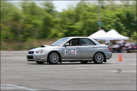 2001 Mercury Grand Marquis - A silver Subaru WRX STI sedan competes on a race track, with tents and cones visible in the background.