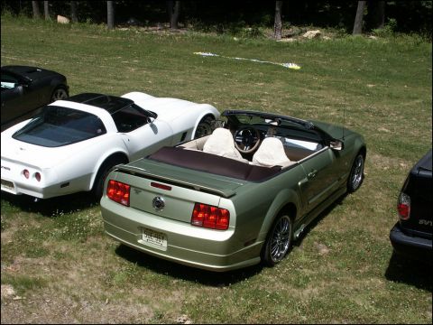 2001 Mercury Grand Marquis - A green convertible Mustang is parked on the grass next to a white Corvette and a black SUV.