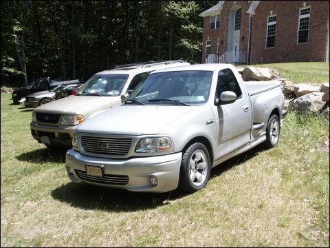 2001 Mercury Grand Marquis - A silver pickup truck is parked on a grassy lawn in front of a brick house.