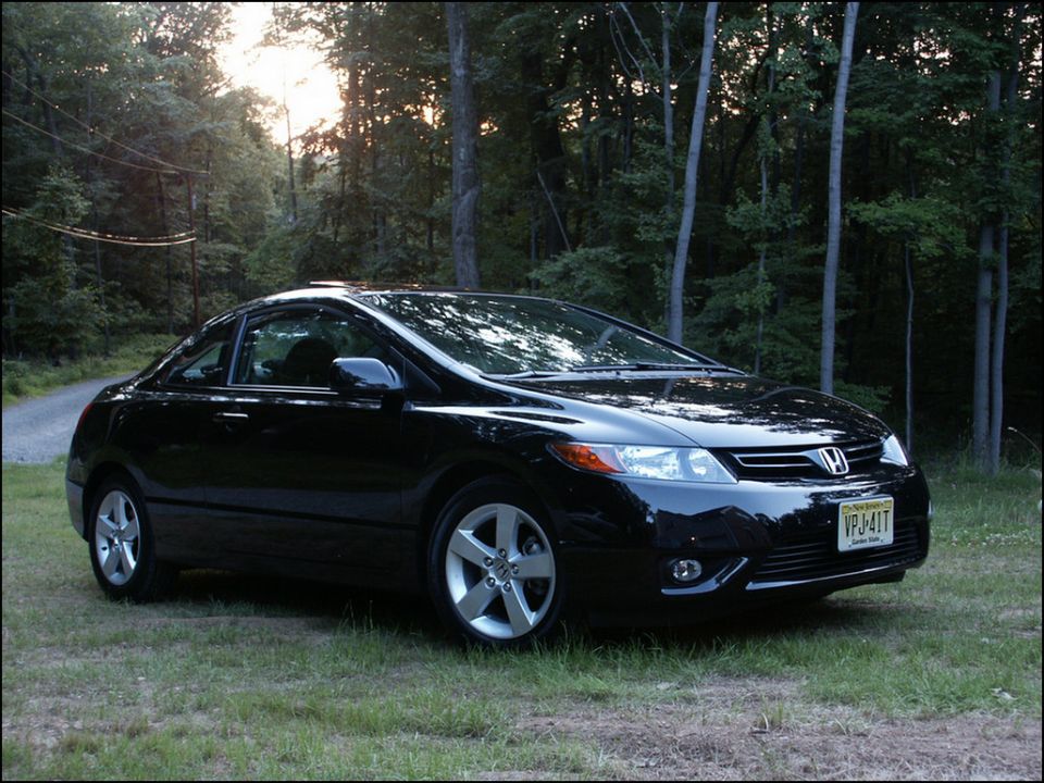 Black Honda Civic coupe parked on grass with trees in background. License plate VPJ-41T