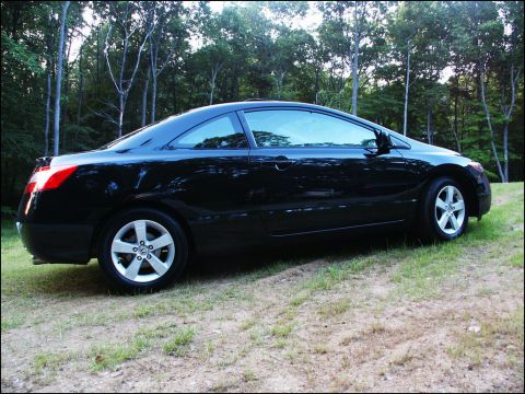 2001 Mercury Grand Marquis - A black coupe is parked on a grassy incline, with a wooded area behind it.