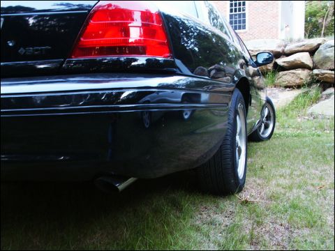2001 Mercury Grand Marquis - The rear of a black 2001 Mercury Grand Marquis is visible from a low angle, parked on a grassy area.