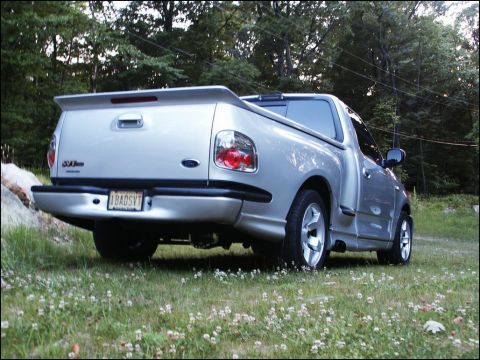 2001 Mercury Grand Marquis - Silver Ford SVT Lightning pickup truck parked on grass with trees in background.
