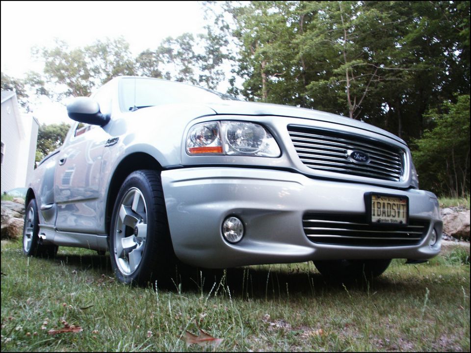 Silver 2001 Ford F-150 SVT Lightning pickup truck parked on grass, front 3/4 view