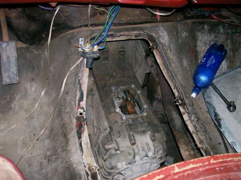 1982 Ford Bronco - This photo shows the interior of a vehicle, focusing on the transmission and floor pan area, with some wiring and a blue bottle present.