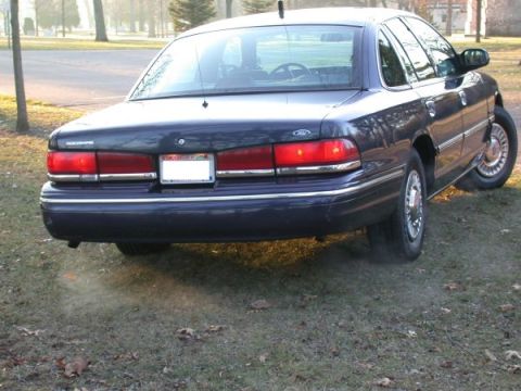 1995 Ford Crown Victoria - The rear of a dark blue 1995 Ford Crown Victoria is shown with a blank license plate.