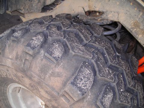 2003 Jeep TJ - A close-up view of a vehicle's tire and suspension system, with an orange strap visible.