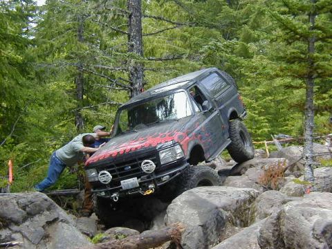 1994 Ford Explorer - Two people help push a modified Ford Bronco through a difficult rocky off-road course.