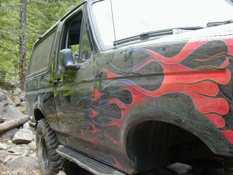 1994 Ford Explorer - Side view of a black SUV with custom flame graphics, seen off-road.