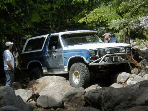 1994 Ford Explorer - A blue and white Ford Bronco navigates a rocky trail with two men observing.